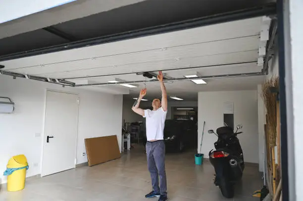 Garage door safety sensor inspection and overhead track repair by a professional technician